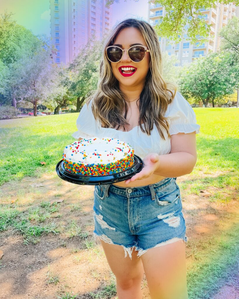 Girl holding birthday cake in park, instagram photo idea, summer outfit ideas, crop top, denim shorts, girl white crop top